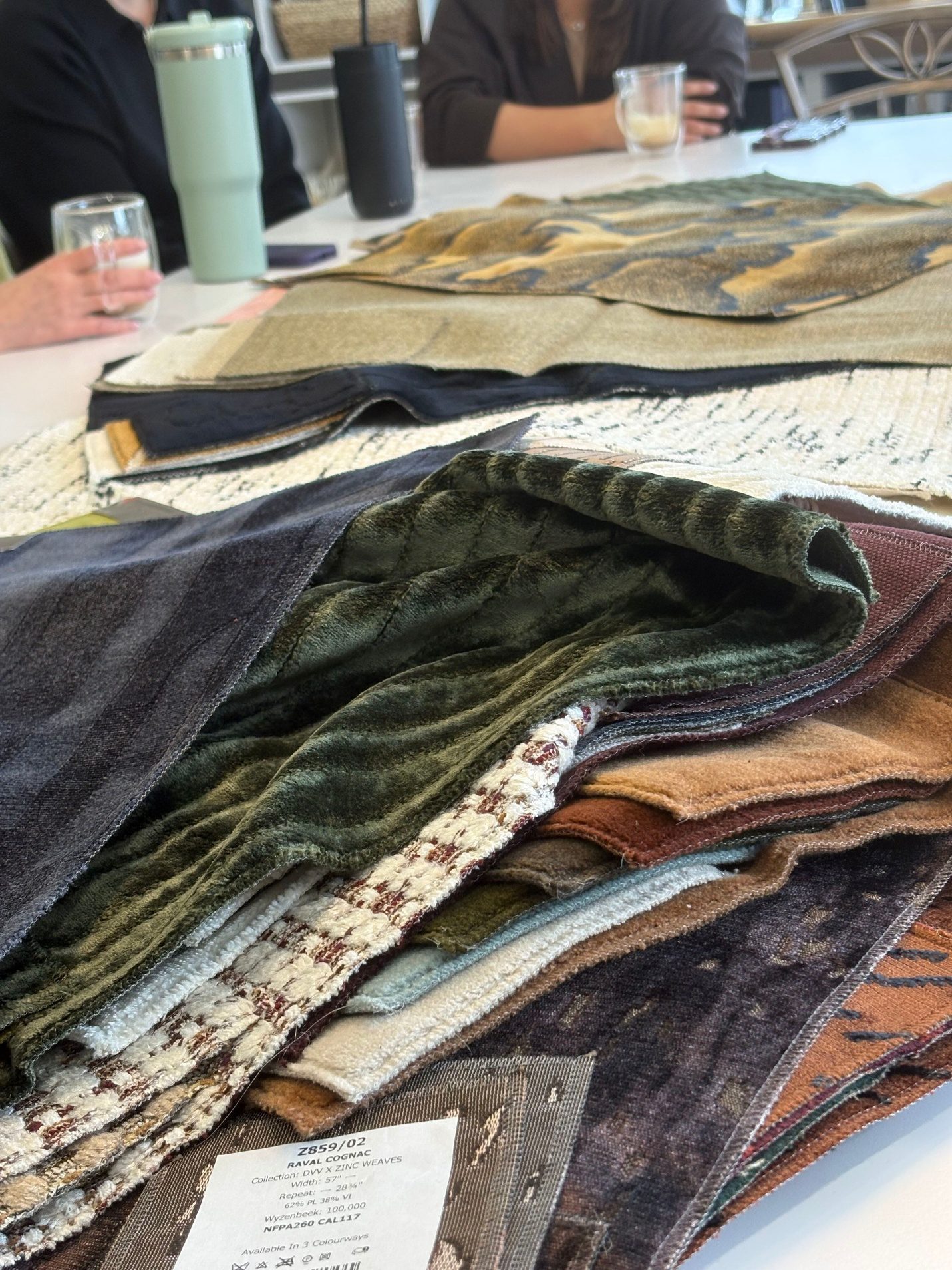 Stack of various fabric swatches on a table.