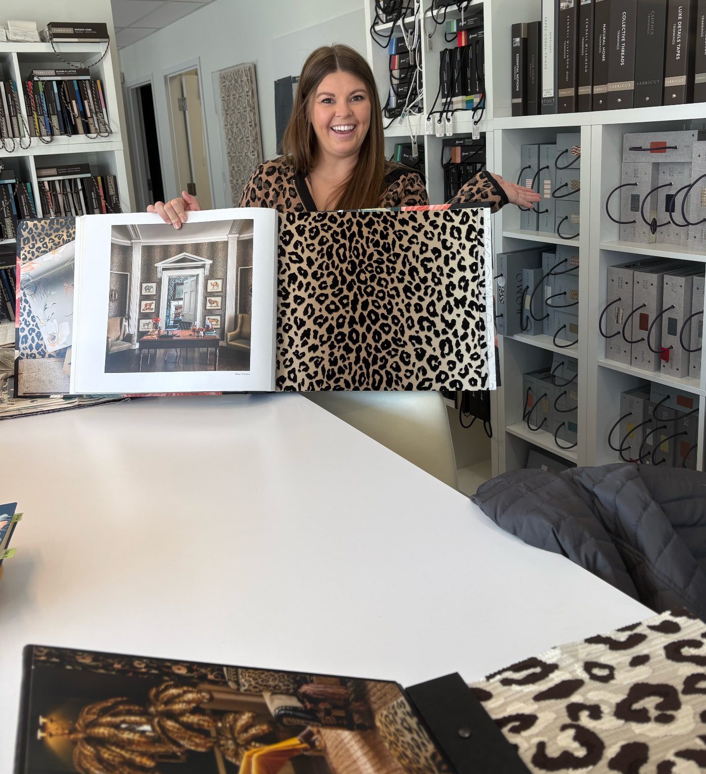 Woman holding two fabric samples in a textile workshop.